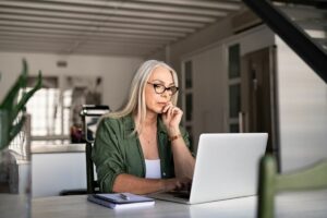Lady in her home sitting at her laptop for an online rehab session