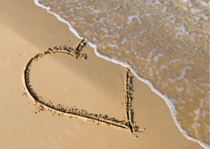 half a heart on the sand with the sea