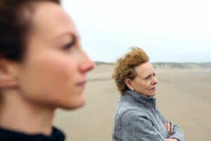 Mother and daughter, standing next to each other, looking out to sea