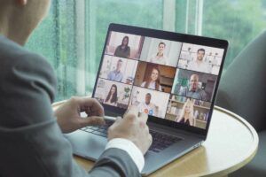 Businessman with laptop, attending online addiction treatment Zoom meeting with other professional people